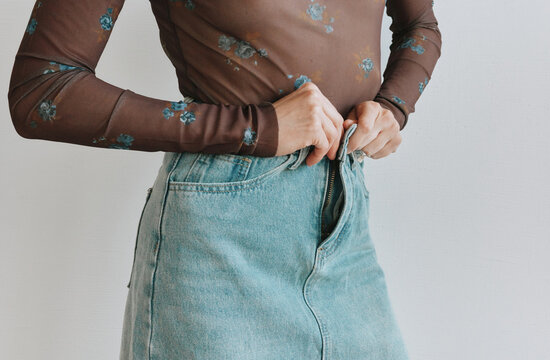Woman buttoning denim skirt