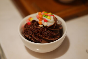 Chocolate ice cream with colorful candies on the white background.