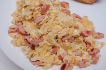 Plate of scrambled eggs with sausage on top