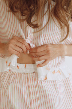 Woman Buttoning Pastel Color Clothes