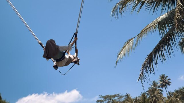 Amusement park dream concept. Happy girl swinging on swing in park at sunset. Child plays with wooden swing childhood dream, airplane pilot flights to sky. Happy family. Girl swinging on swing in park