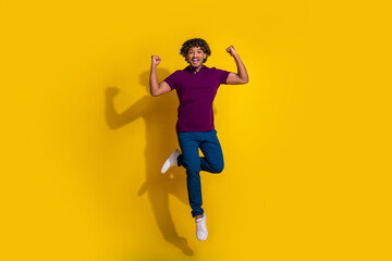 Fototapeta na wymiar Full size photo of nice young man jump raise fists win lottery wear trendy violet outfit isolated on yellow color background