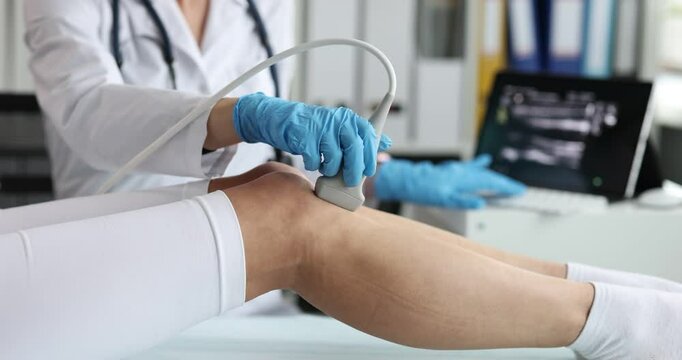 Doctor applies ultrasound probe to legs of female patient. Lady physician evaluates blood flow detecting varicose veins and vascular problems