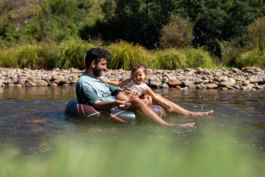 A dad playing with his toddler on the river with a river tub