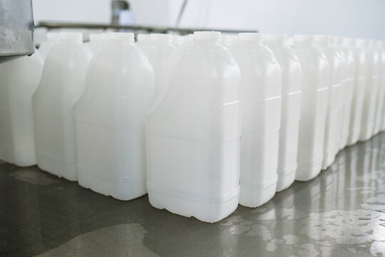 Many white plastic gallons standing in dairy factory