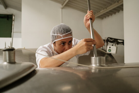 Cheese factory worker checking milk storage tank
