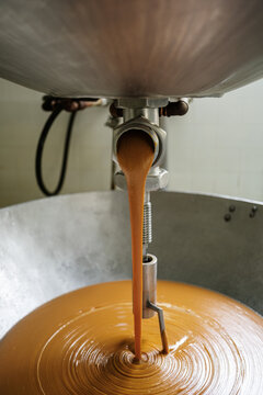 Caramel flowing into industrial mixer in food factory