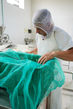 Cheesemaker covering container with net in factory