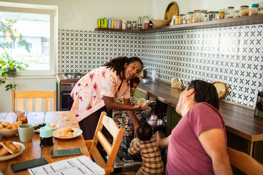 Family working together in the kitchen unloading dishwasher