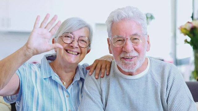 Sixty years couple, elderly parents communicates with grown up children using modern technologies makes video call, wave hands gesture of hello or goodbye sign, older generation and internet concept
