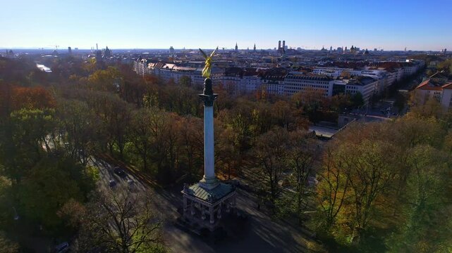 4K Aerial drone view of golden statue Nike of Paionios, angel symbol of piece, Friedensengel statue overlooking the city center Munich on a sunny warm autumn day by the river Isar