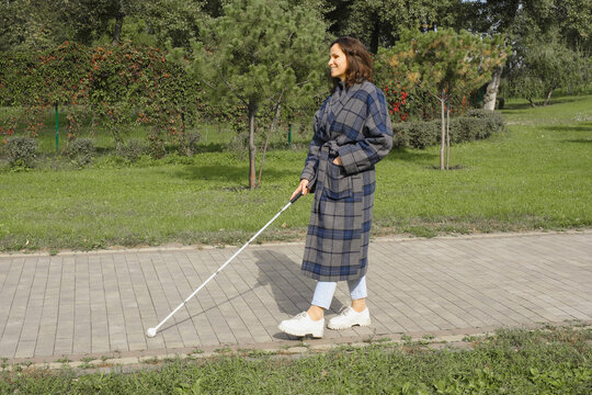 Confident blind woman walking with cane in park