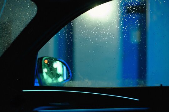 Raindrops on a car window at night in neon glow