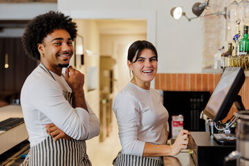 Two smiling cashiers posing at restaurant cash register