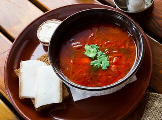 Ukrainian borsch red soup with pork and sour cream , served with bread and salo