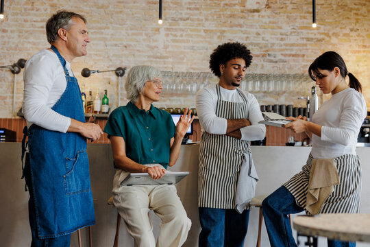 Restaurant staff meeting with manager holding digital tablet