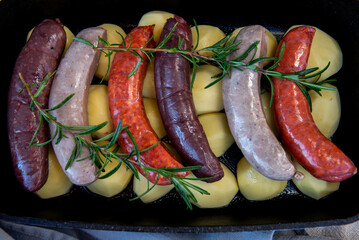 Close-up of bowl with raw homemade blood sausage, pork sausage and chorizo in oven with potatoes....