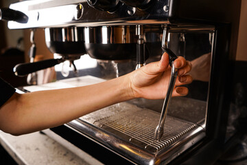 Making coffee in a cafe with a professional coffee maker. A hand holds a coffee machine. In a coffee shop.