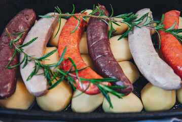 Close-up of bowl with raw homemade blood sausage, pork sausage and chorizo in oven with potatoes. homemade traditional food
