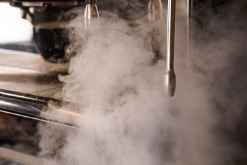 Lots of steam from the coffee maker. the coffee maker smokes and smokes. surface steam treatment in a cafe. concept of making coffee.