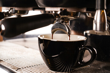 Pouring coffee stream from professional machine in cup. Barista man making double espresso, using filter holder. Flowing fresh ground coffee. Drinking roasted black coffee in the morning.