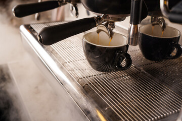 Espresso coffee extraction from a professional coffee machine with a bottomless filter, Close-up of a coffee drop from the coffee machine.