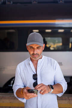 man at train station using mobile phone