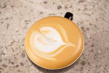 Valentine's Day. A cup of cappuccino coffee with a heart shape and on a dark background, in a coffee shop. View from above.