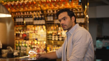 Sitting smart man drinking alone of cocktail Old fashioned waiting friends or couple at bokeh lighting at luxurious beverage counter nightclub at pub and restaurant on Friday meeting night. Vinosity.
