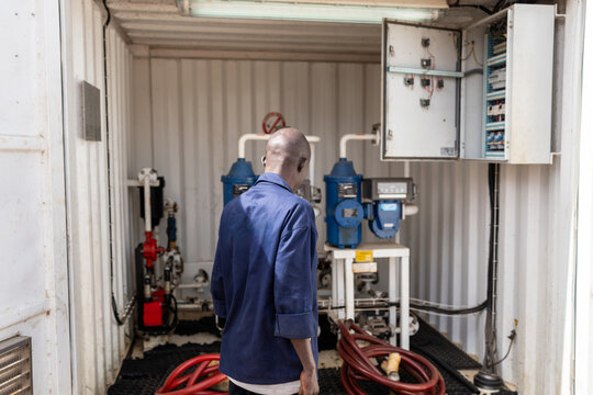 African engineer inspecting water treatment equipment inside container