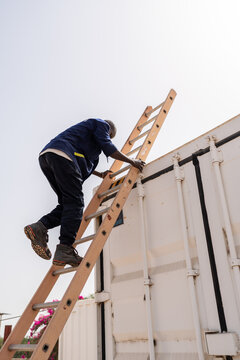 African technician climbing a ladder to access the roof