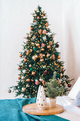 Beautifully decorated bedroom features a tall Christmas tree adorned with lights and ornaments background. A small festive centerpiece sits on wooden tray, adding to the cozy atmosphere.