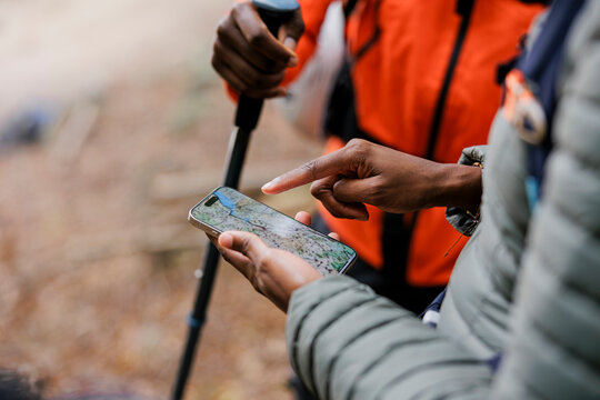Hikers using smartphone gps app for navigation in forest