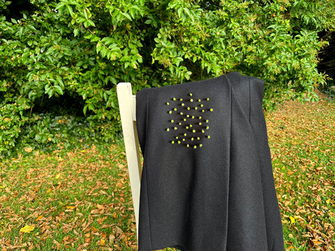 Sticky goosegrass seeds on overcoat slung over garden chair