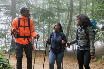 Backpackers hiking together in misty forest