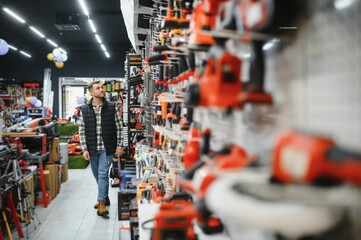 A man chooses a power tool in a hardware store