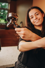 Smiling warmly, the barista expertly holds the holder in his hands, creating a perfectly crafted cappuccino for the waiting customer.