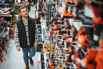 A man chooses a power tool in a hardware store