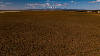 Fototapeta premium MARCH 2024, EGNAR COLORADO/UTAH BORDER - USA - Egnar Colorado on Utah border, near Blanding shows planted fields in early spring with snow capped Abajo Mountains