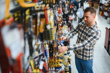 A man in a hardware store choosing a tool