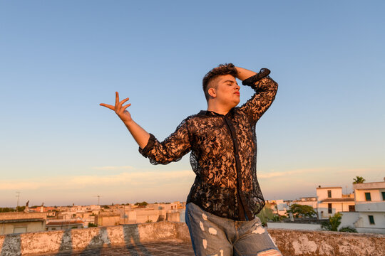 Non-binary person dancing on the roof at sunset