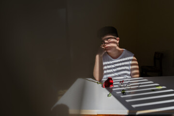 Non binary person with closed eyes and rose, portrait in a shadows