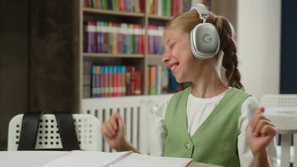 Caucasian teen girl student schoolgirl daughter pupil listening music audio song in headphones happy child kid listen sound earphones studying class lesson learning break fun smiling dancing in school