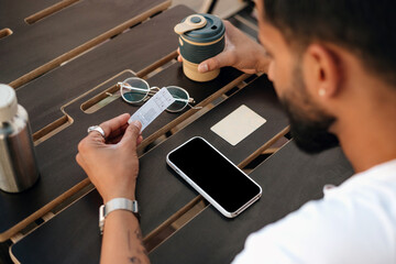 An Indian man drinking coffee from reusable cup in street cafe.