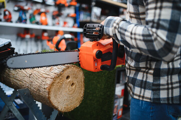 Male worker choosing modern electric chain saw