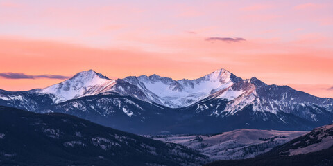 Obraz premium A dramatic mountain range at twilight with jagged peaks, snow-dusted slopes, and a glowing pink and orange sky. The majestic setting feels powerful and timeless.