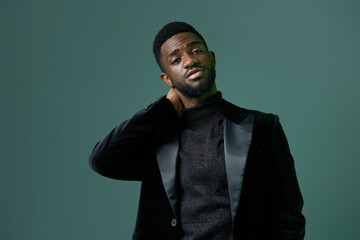 Confident businessman in a sleek black suit and turtleneck standing against a vibrant green background