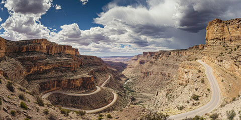 Fototapeta premium A dramatic mountain pass with sheer cliffs, a winding road cutting through the landscape, and a dramatic sky filled with clouds. The rugged and adventurous setting feels awe-inspiring.