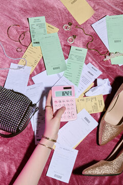 Person Calculating Expenses Amidst Stylish Accessories and Receipts