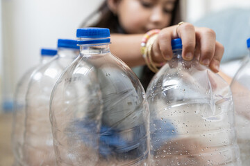 Close-Up Of Child Handling Plastic Bottles For Craft Project